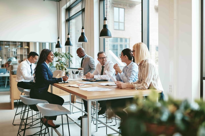 Workers collaborating at a long desk due to workplace design elements 