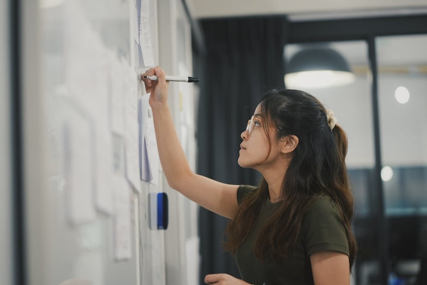 business woman writing on whiteboard in office