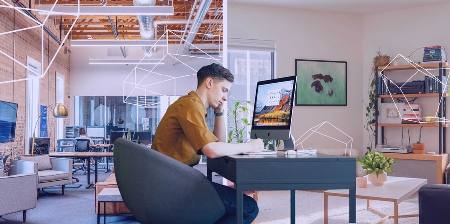 employee in yellow shirt working at desk in hybrid office space