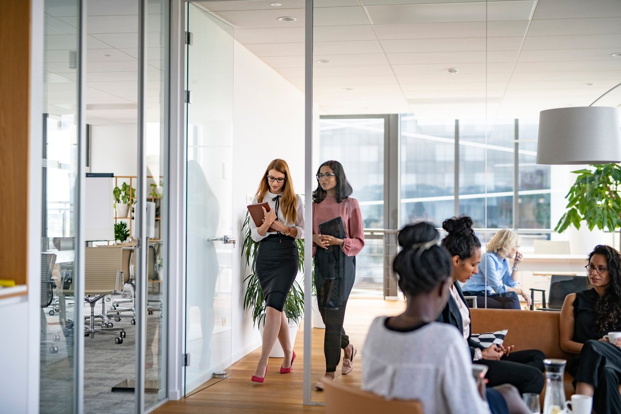 2 business woman walking in doorway of a office collaboration space