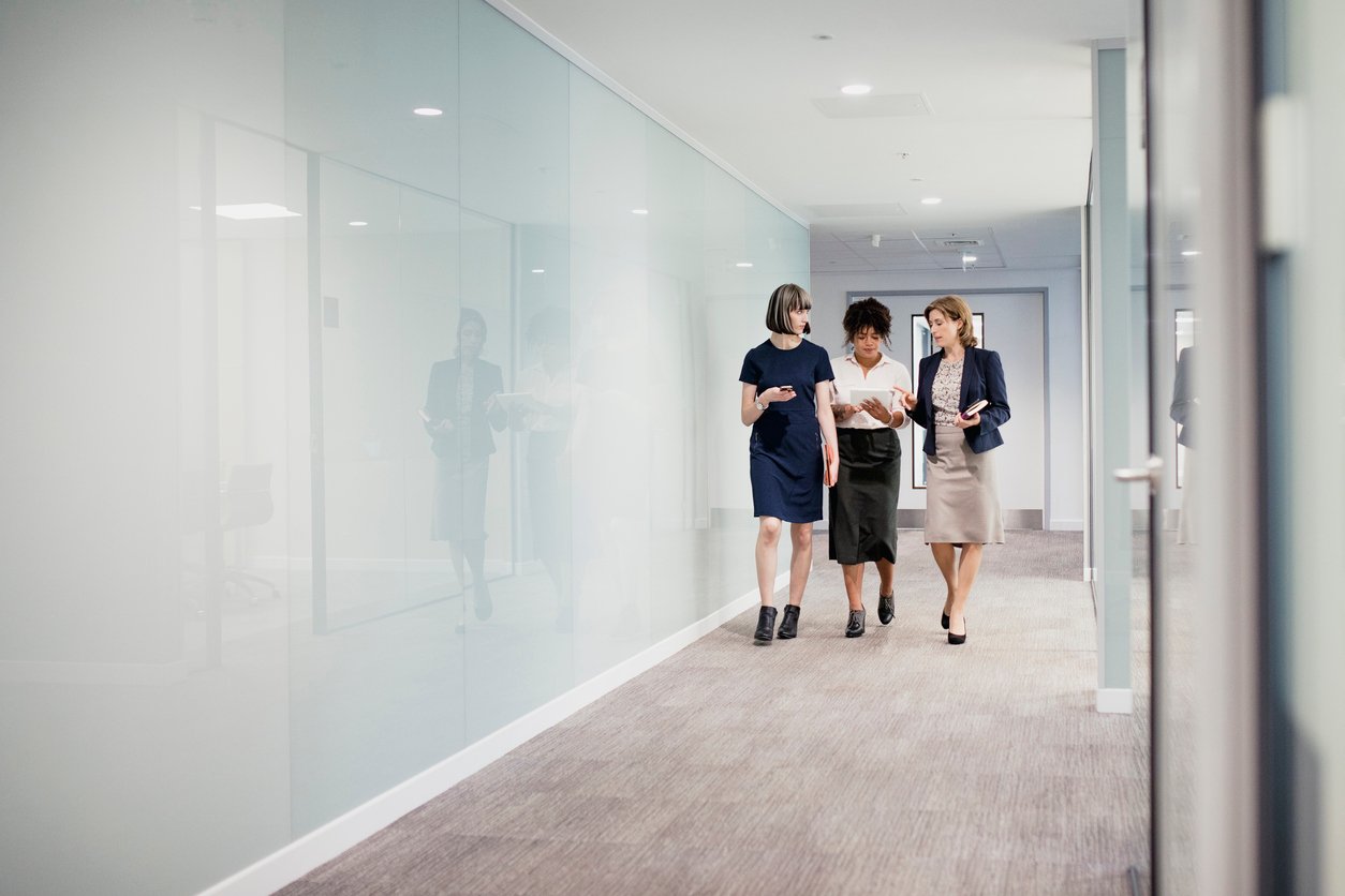 3 business woman walking in office hallway
